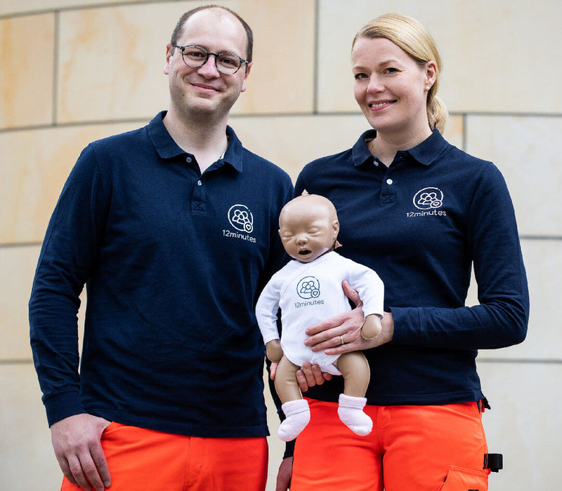 articles/Babybox-and-Family-12-Minutes-Erste-Hilfe-Elena-Lukas-mit-Notfallpuppe-June-vor-Ambulanz-Nahaufnahme_1.jpg