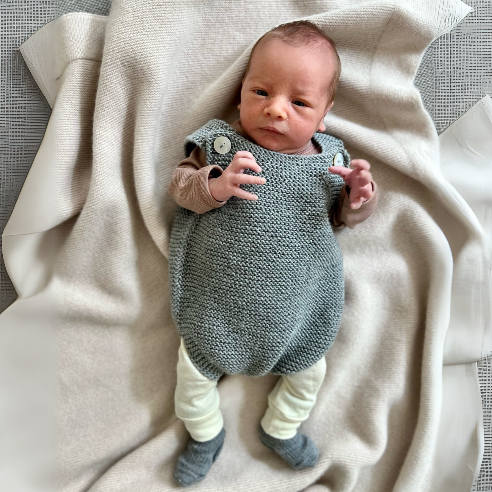 Baby mit handgestricktem Romper in grau