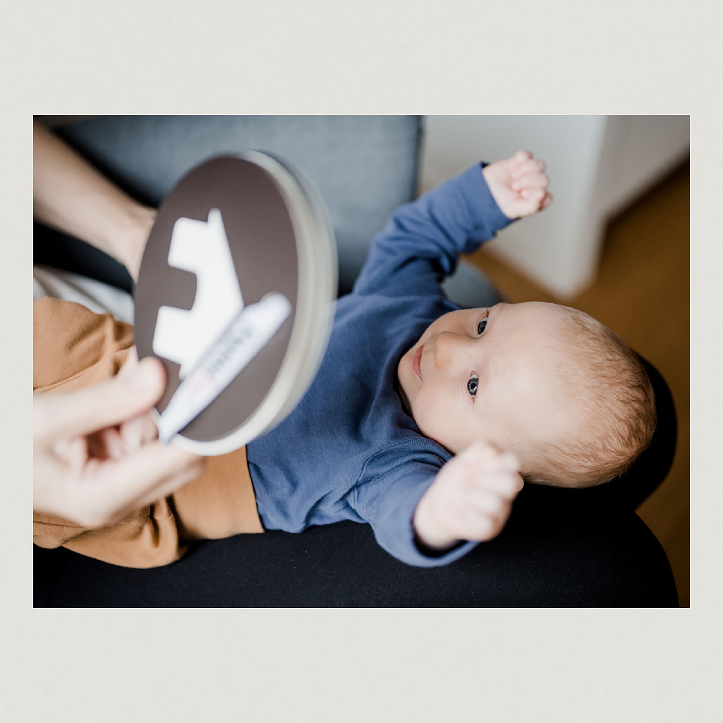 Foto eines liegenden Babys, welches eine Kontrastkarte vorgehalten bekommt.