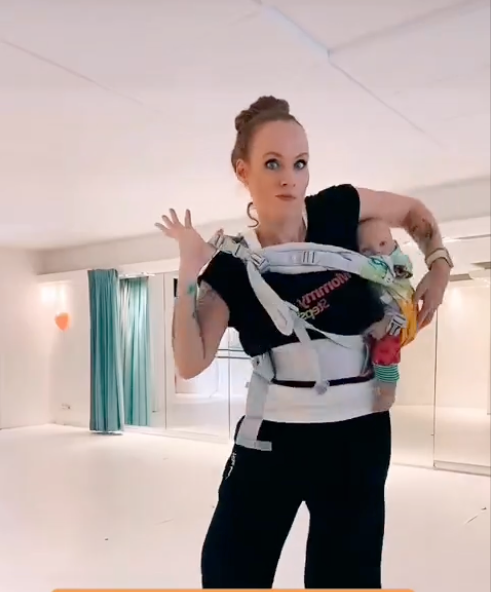 Frau die ihr Kind in einer Trage auf dem Rücken trägt