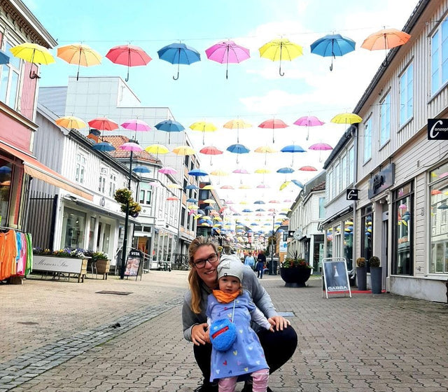 Mutter mit Kind in einer Strasse mit Regenschirmen