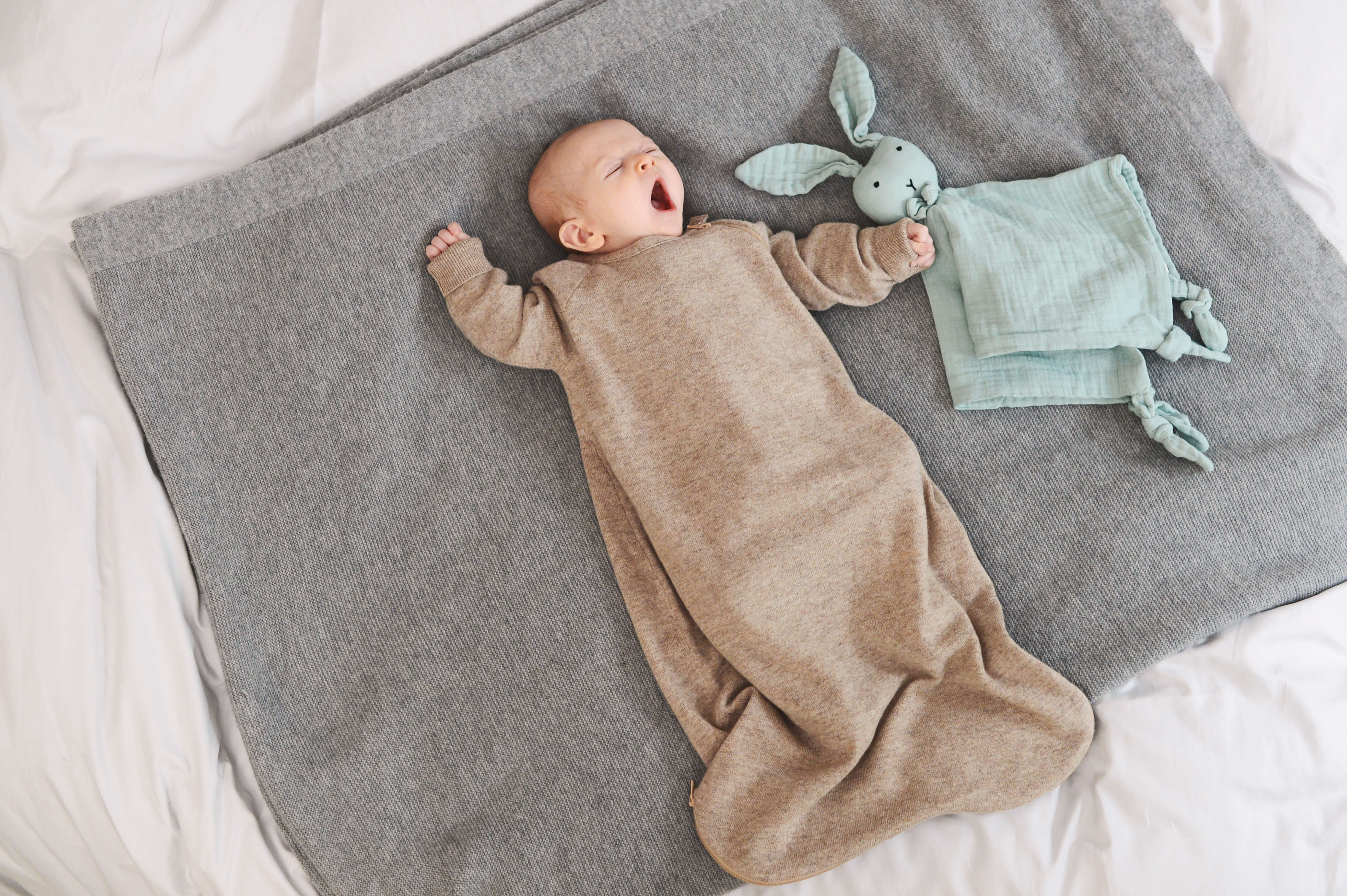 Baby gähnend auf einer Decke im Schlafsack