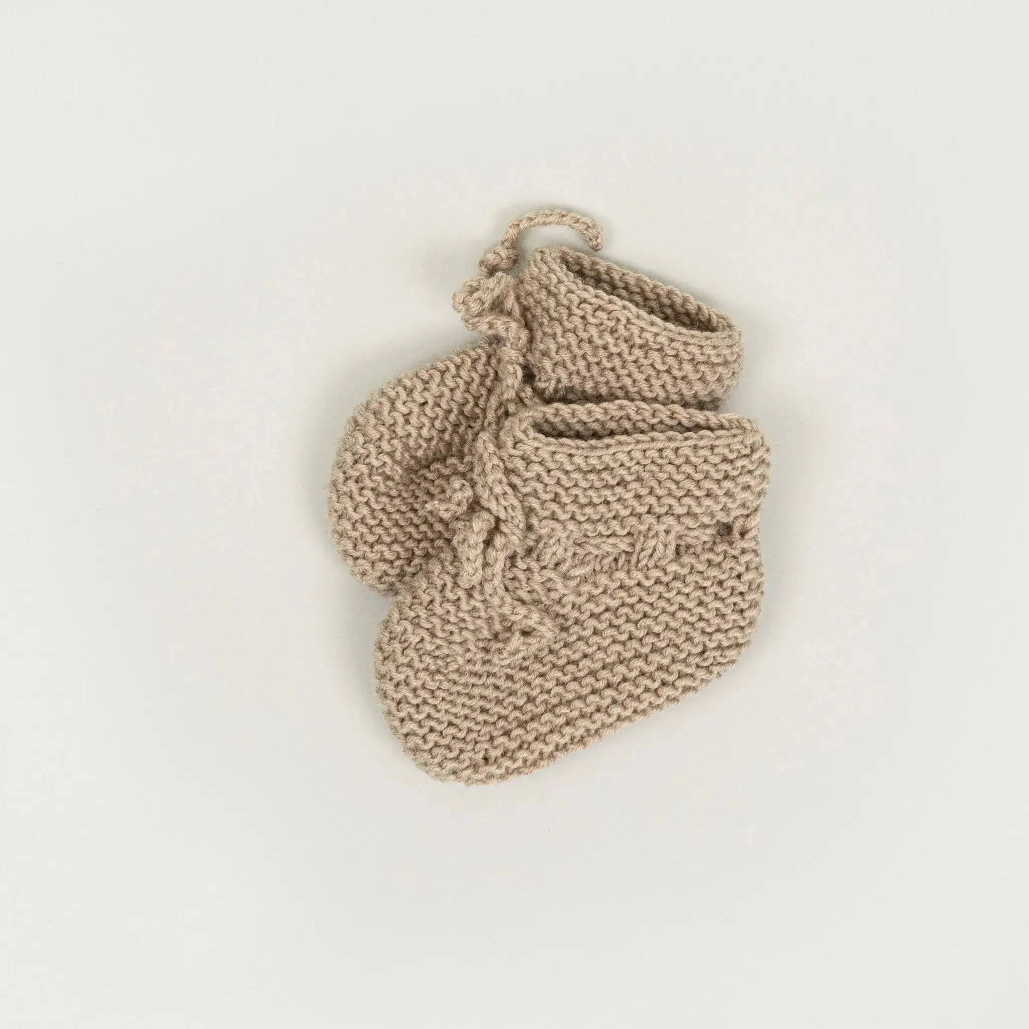 Ein Paar handgestrickte Schuhe aus der Babybox Handmade Collection in der Farbe sand in der Größe 56/62