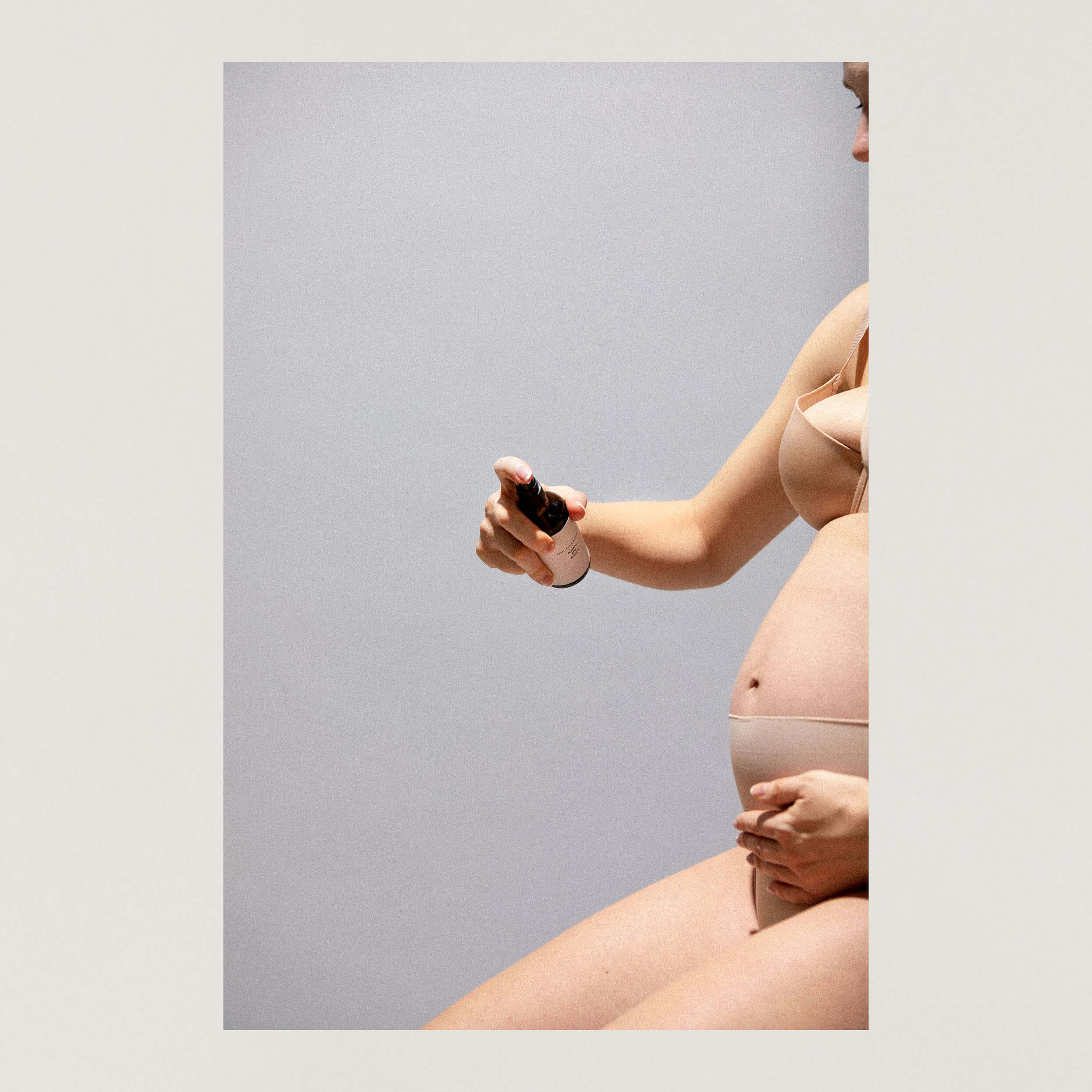 Mood Foto Schwanger mit nacktem Bauch die sich mit Öl einsprüht