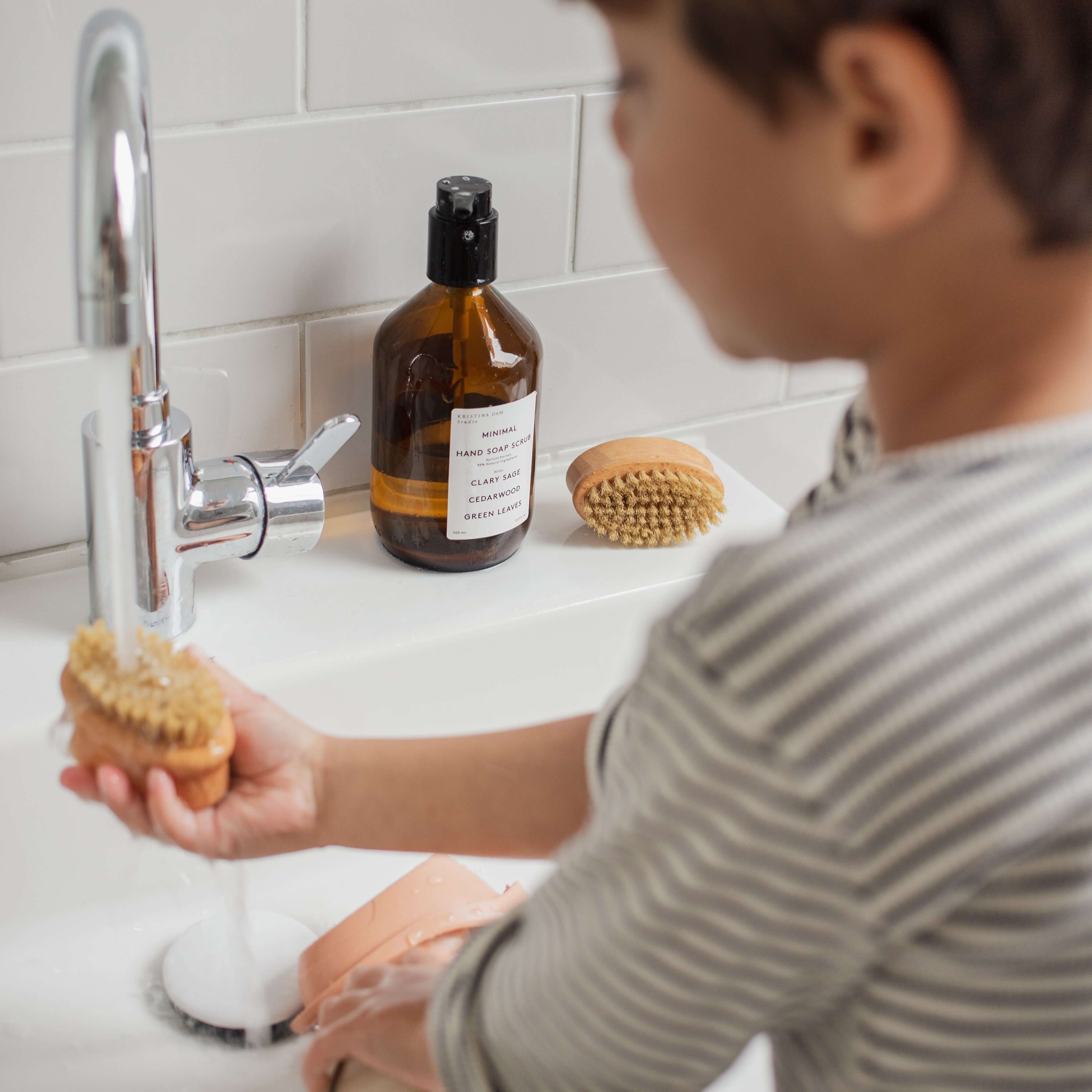 Kind hält Bürste unter den Wasserhahn
