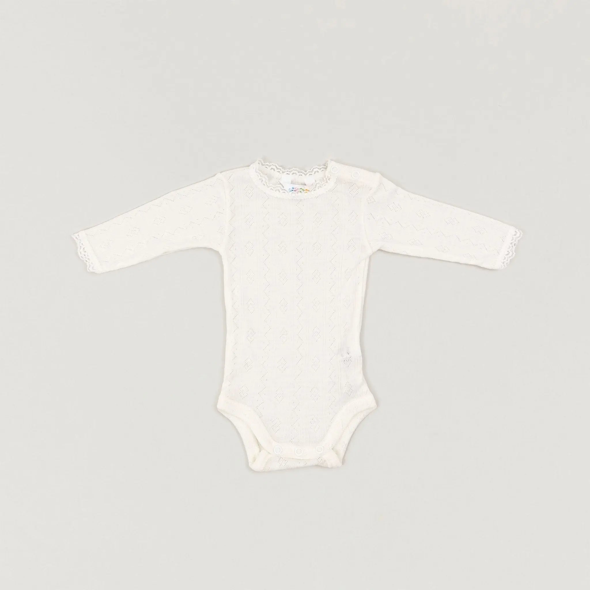Das Produktbild eines naturefarbenen Langarmbodys mit Rüschen aus Wolle und Seide der Firma Joha in der Frontalansicht im Onlineshop von Babybox and Family