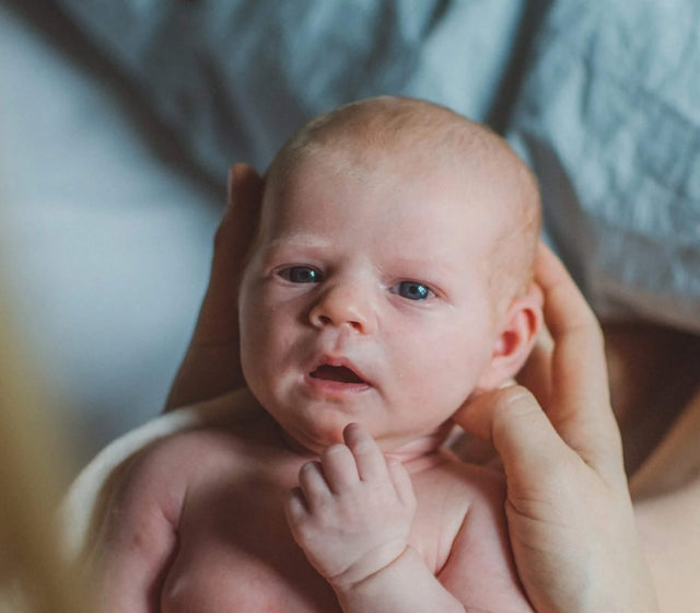 Babykopf in den Händen der Mutter