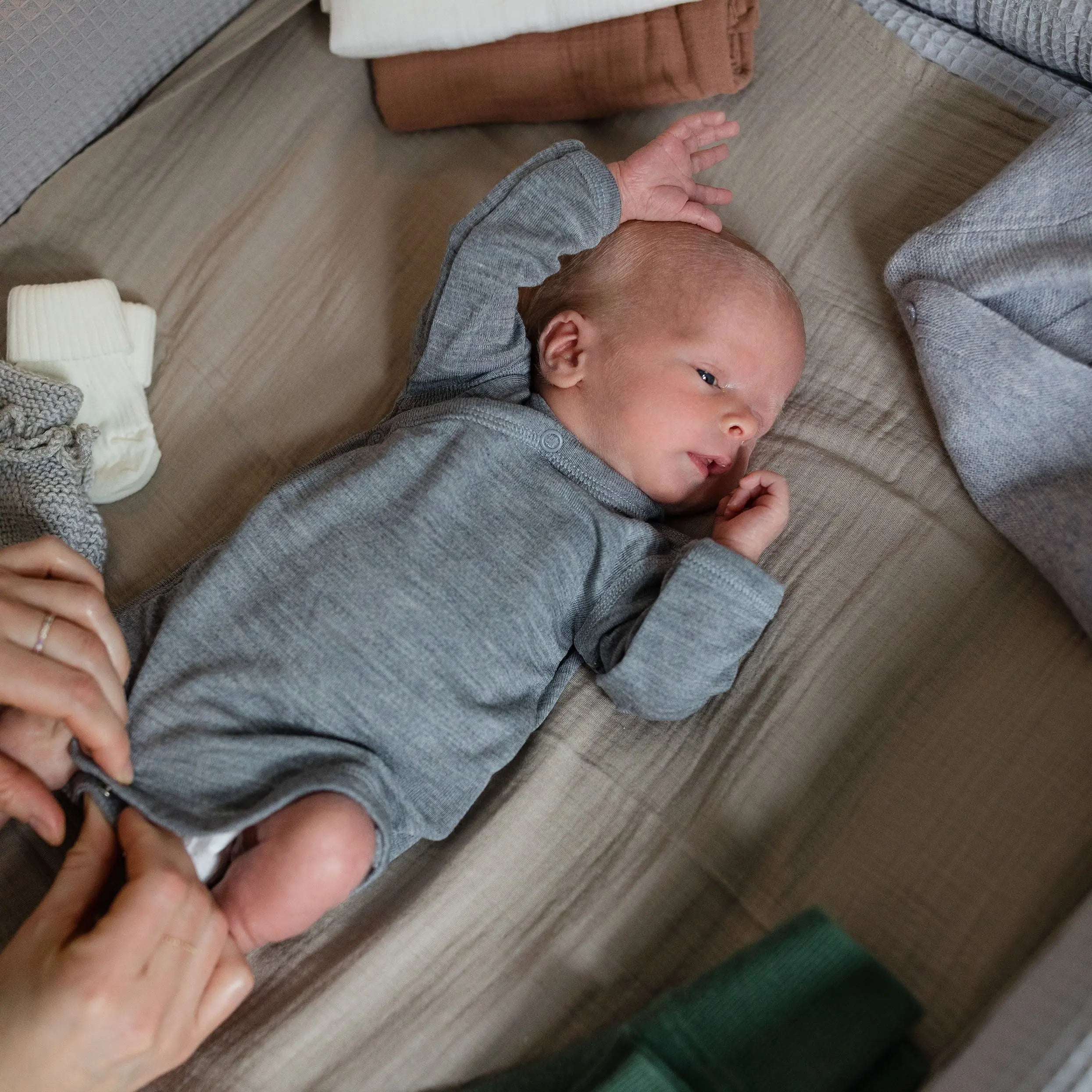 Ein Tragebild des Langarmwickelbodys aus Wolle und Seide in Grey-Melange der Babybox Collection am Baby im Onlineshop von Babybox and Family